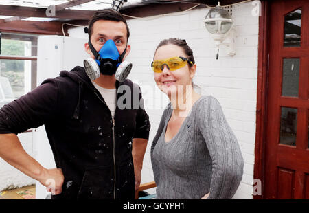Junger Mann mit einer schützenden Bauherren Maske küsst seine Frau oder Freundin Stockfoto