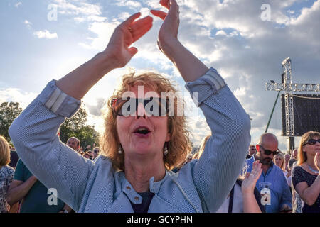 Reife Frau Jubel bei einem Rockkonzert in einer Menschenmenge UK Stockfoto