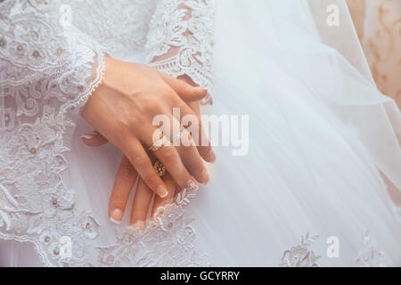 Weiße Hochzeit Spitzenkleid mit langen Ärmeln. Die Hände von Frauen. Ehering Stockfoto