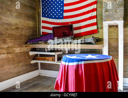 Eine amerikanische Flagge hängt an der Wand ein Raum aus Holz mit Regalen halten Musikinstrument Fälle mit TN Staatsflagge über Tisch Stockfoto