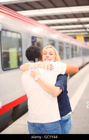 Interracial paar umarmt am Bahnhof Stockfoto