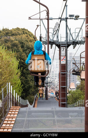 Japan, Iyo Matsuyama Schloss. Seilbahn, Sessellift, auf und zusammen mit der Stadt Hintergrund mit kleinen Jungen vorne in blau Hoodie Top. Stockfoto