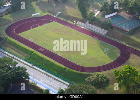 Blick aus der Vogelperspektive auf ein Schulfußballfeld, zwei Plätze für Basketball und Tennis und Laufbahnen. Singapur. Stockfoto