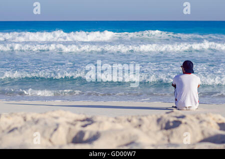 ein Mann sitzt allein mit Blick auf das Meer Stockfoto