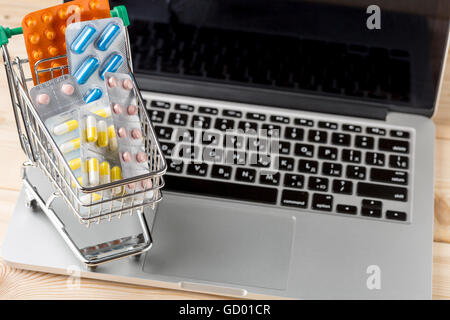 Mini-Warenkorb mit Pille Blisterpackung auf offenen Laptop. Konzept Forn Online-Shop Stockfoto