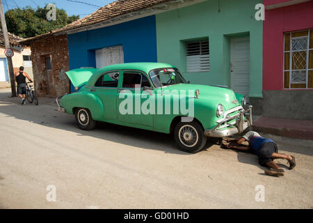 Eine kubanische Mann liegt unter der Vorderseite des seinen fünfziger Jahre amerikanische Oldtimer einige Wartungsarbeiten Stockfoto