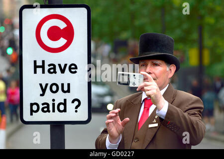 London, England, Vereinigtes Königreich. Hotel-Portier nehmen ein Foto von einer Demonstration in der Park Lane, neben einer City-Maut-Schild Stockfoto