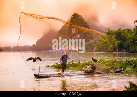 Traditionelle chinesische Kormoran Fischer wirft ein Netz auf dem Li-Fluss in Yangshuo, China. Stockfoto