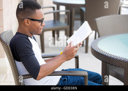 Closeup Portrait, intelligente nerdy Jüngling mit großen schwarzen Gläsern, sitzen und lesen, isoliert im freien Hintergrund. Stockfoto