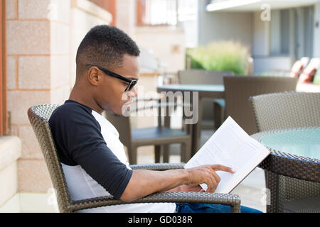 Closeup Portrait, intelligente nerdy Jüngling mit großen schwarzen Gläsern, sitzen und lesen, isoliert im freien Hintergrund. Wissensarbeiter Stockfoto