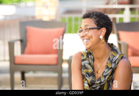 Closeup Portrait, Reife Frau mit Brille lächelnd, isoliert im freien Hintergrund mit Patio-Möbel Stockfoto