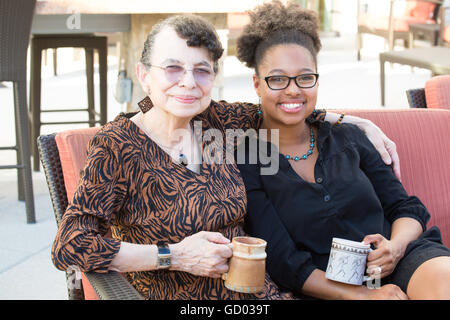 Closeup Portrait, Enkelin und Großmutter sitzt, isoliert Getränke Kaffee und Tee zusammen, genießen im freien Hintergrund Stockfoto
