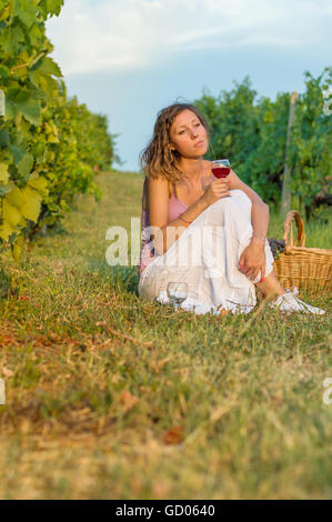 Mädchen mit Glas Wein sitzen im Weinberg Stockfoto