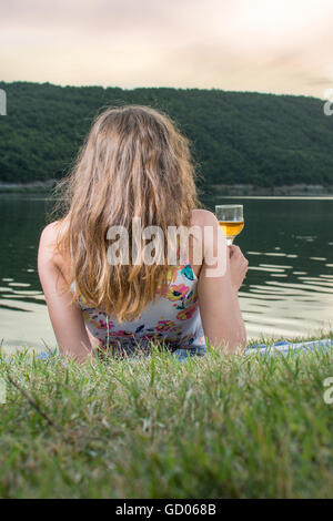 Frau mit einem Glas Wein am See Stockfoto