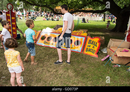 Kinder spielen Ball in einem Eimer Spiel auf der jährlichen Barnes Village Fair auf Barnes Common im Südwesten von London, England, Großbritannien Stockfoto