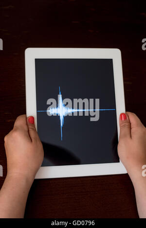 Frau Hand zeigt eine blaue Erdbeben mit einem schwarzen Hintergrund auf eine weiße Tablette Stockfoto
