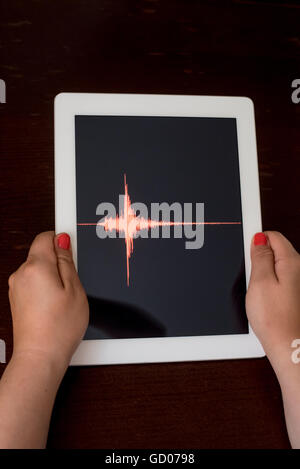 Frau Hand zeigt eine rote Erdbeben mit einem schwarzen Hintergrund auf eine weiße Tablette Stockfoto