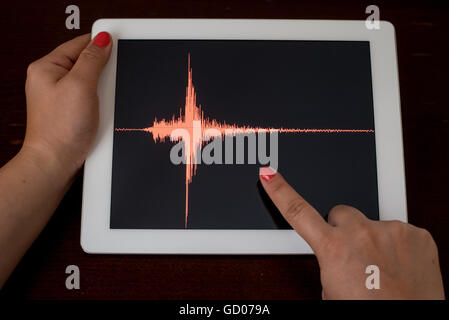 Frau Hand zeigt eine rote Erdbeben mit einem schwarzen Hintergrund auf eine weiße Tablette Stockfoto