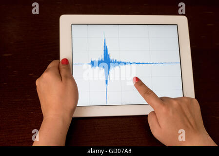 Frau Hand zeigt eine blaue Erdbeben mit einem weißen Hintergrund auf eine weiße Tablette Stockfoto