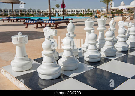 Nahaufnahme der Spielsteine auf riesigen Schachbrett Spiel in Tropical Hotel Resort mit Swimmingpool Stockfoto