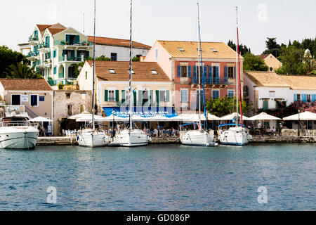 Bunte Kai View - Yachten vor Anker im Hafen von Fiskardo, mit Restaurants und traditionellen Gebäuden, Kefalonia, Griechenland. Stockfoto