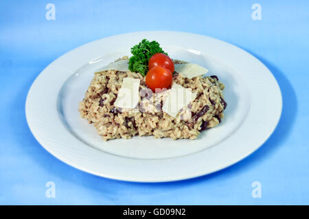 Moderne Küche auf einem weißen Teller und blauem Hintergrund - italienische cremigen Risotto mit Pilzen und Sahne Stockfoto