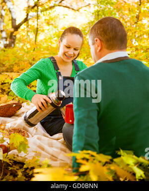 Schwangere Paare Picknick im Herbst Park haben. Glückliche Familie im Freien. Lächelnder Mann und Frau Entspannung im park Stockfoto