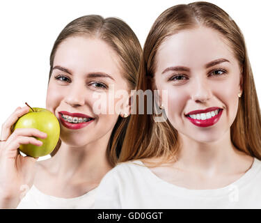 Junge Frau mit Klammern an Zähnen essen Apfel Stockfoto