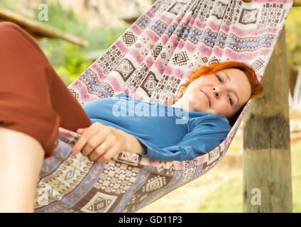Frau in Hängematte auf der Terrasse des ländlichen Holzhaus liegt Stockfoto