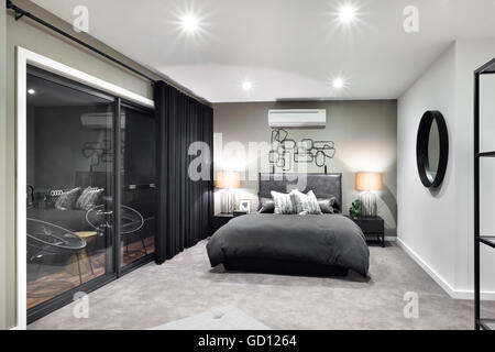 Schwarze Farbe Bett im luxuriösen Hotel oder Haus mit blinkenden Lampen neben Glas Türen und Fenster Stockfoto
