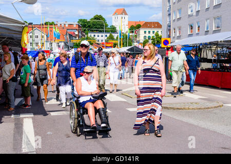 Ronneby, Schweden - 9. Juli 2016: Grosse öffentliche Markttag in der Stadt mit vielen Menschen. Hier ist eine weibliche Person in einem Rollstuhl Pusche Stockfoto