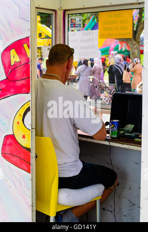 Ronneby, Schweden - 9. Juli 2016: Große öffentliche Markt Tag in der Stadt mit vielen Menschen. Hier ein Mann sitzt in einem Ticket Booth mit Pe Stockfoto