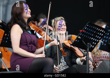 Mitglieder des Orchesters Rogue mit Gesichtern bemalt wie Ziggy Stardust führen ein David Bowie Tribute setzen auf der Hauptbühne am dritten Tag des T im Park, das jährliche Musikfestival Schloss Strathallan, Perthshire. Stockfoto