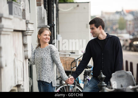 junges Paar, Mann und Frau in Amsterdam, Niederlande, die Hände vor der Eingangstür, mit jeweils anderen Stockfoto
