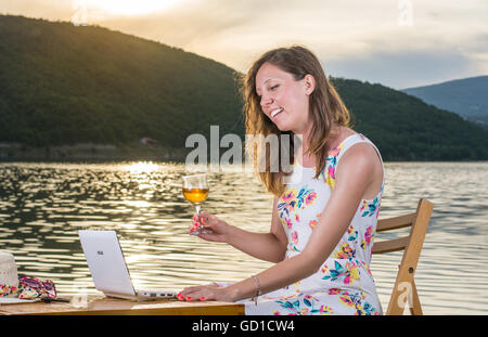 Junge Frau, die einen Videoanruf am See Stockfoto