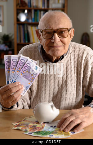 Greis, Senior, 92 Jahre alt, Sparschwein mit Euro-Banknoten Stockfoto