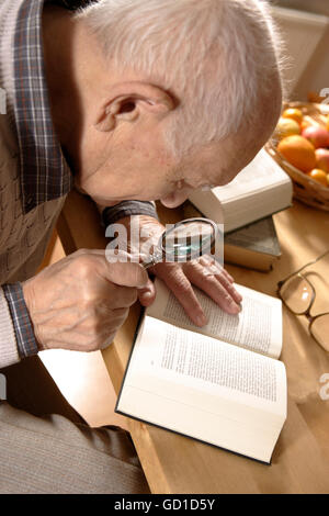 Greis, Senior, 92 Jahre, mit Buch und Lupe Stockfoto