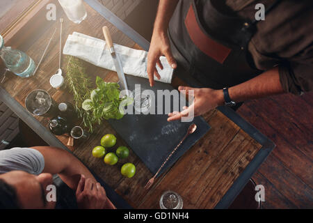 Draufsicht auf zwei Barkeeper diskutieren über neue cocktail-Rezept mit Zutaten auf der Bar Theke. Stockfoto