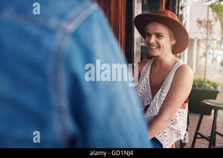 Lächelnde junge Frau mit ihrer Freundin in einem Café sitzen. Junge Menschen an einem Cafétisch sitzen. Stockfoto