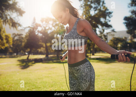 Außenaufnahme einer Frau in Sportbekleidung, die draußen in einem Park mit Seilspringen trainiert. Fitnesstraining-Frau mit Sprungseil Stockfoto