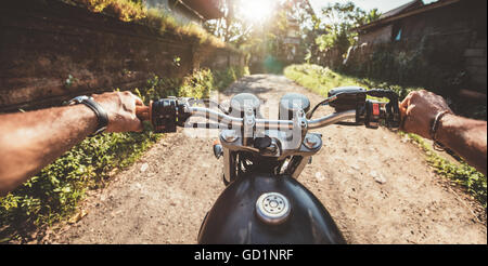 Fahrer fahren Motorrad auf der Landstraße. Point Of View mit Schwerpunkt Motorrad Lenker und Mann Hände geschossen. Stockfoto