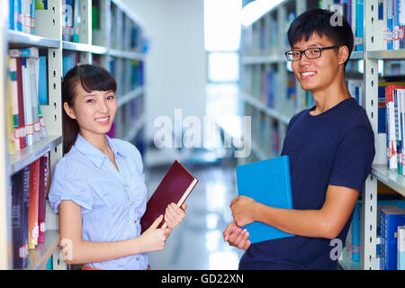zwei junge asiatische Studenten Lächeln in die Kamera in die libray Stockfoto