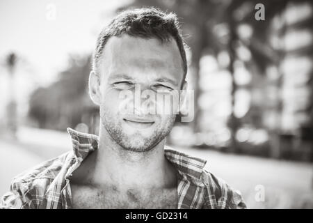 Lächelnde junge hübsche kaukasischen Mann, Outdoor-Porträt in stilisierten Sonnentag, schwarz / weiß Foto Stockfoto