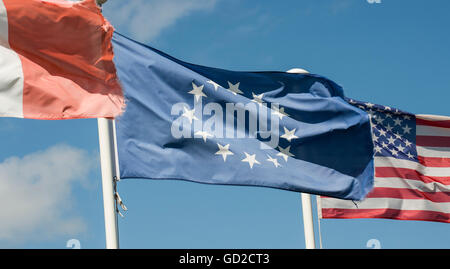 Französische, europäische und amerikanische Flaggen im Wind auf weißen Fahnenmasten mit blauen Himmel und flauschigen Wolken im Hintergrund wogenden Stockfoto