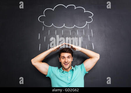 Lächelnd jungen Mann Hand in Hand über Kopf und Decke aus gezeichneten Regen über Tafel Hintergrund Stockfoto