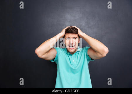 Porträt von ein verrückter junge Mann schrie isoliert über schwarze Tafel Stockfoto