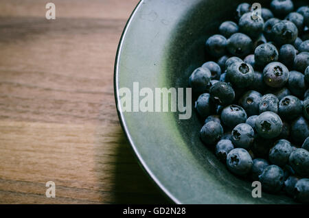 Heidelbeeren in einer Schüssel auf ein Holz Schneidebrett. Stockfoto