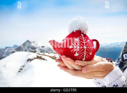 Teekanne in verknoteten GAP in den Händen einer Frau gegen Bergkulisse Stockfoto