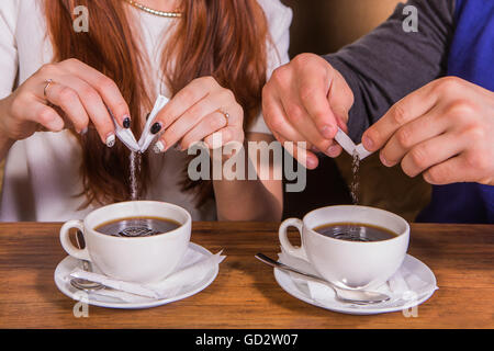 Hände einer Frau und ein Mann, der Zucker in einer Tasse. Stockfoto