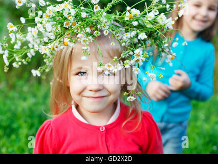 Porträt von zwei kleine Schwestern im Freien tragen Kranz aus weißen Margeriten in Sommertag Stockfoto